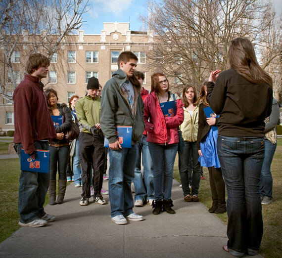 Students on a campus tour with Desmet hall in the background. 
