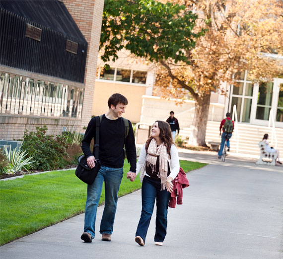 students walk holding hands on campus 