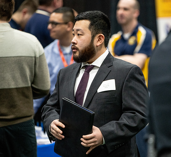 Professionally dressed students with portfolio moves through career fair