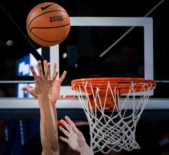 Outstretched arms of a Gonzaga basketball player going for a rebound near the hoop. 