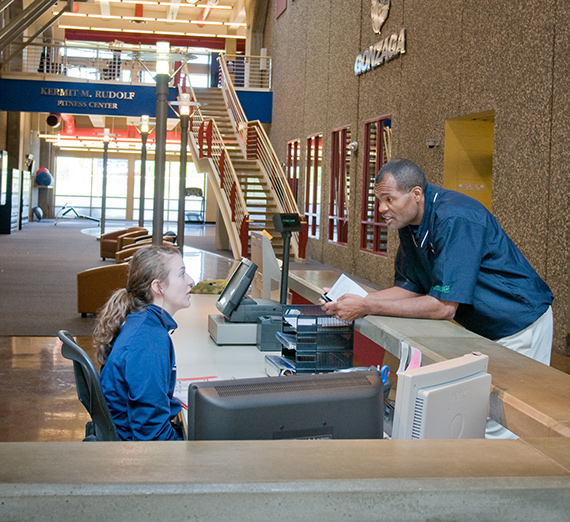 A man receives assistance at the front desk of the Rudolf Fitness Center