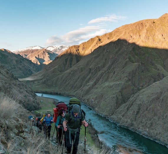 Hiking trail with mountains in background and river below