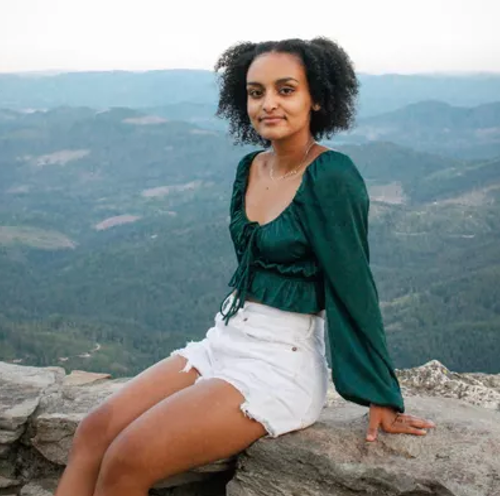 Mieri Kahsay sitting on a rock wall outside