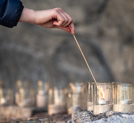 A student lights a prayer candle in the Grotto
