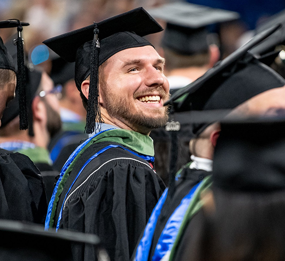 man in graduation robe smiling
