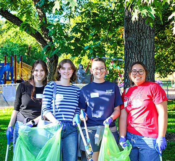 Four people holding trash bags.