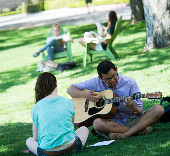 students playing guitar on the lawn 