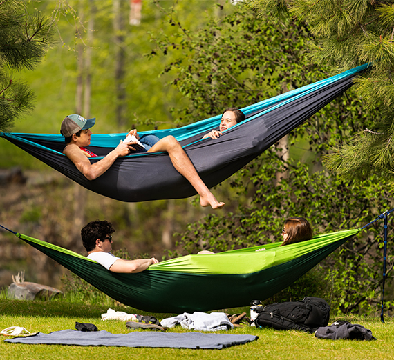 Four students lay in hammocks by Lake Arthur.