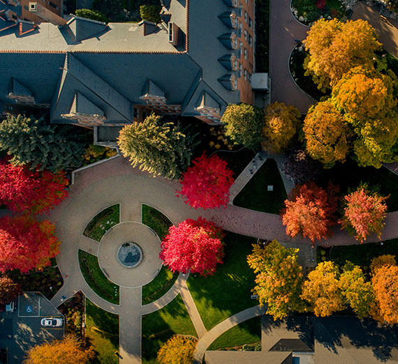 Looking down from a drone over College hall with fall colored red, orange and yellow leaves.