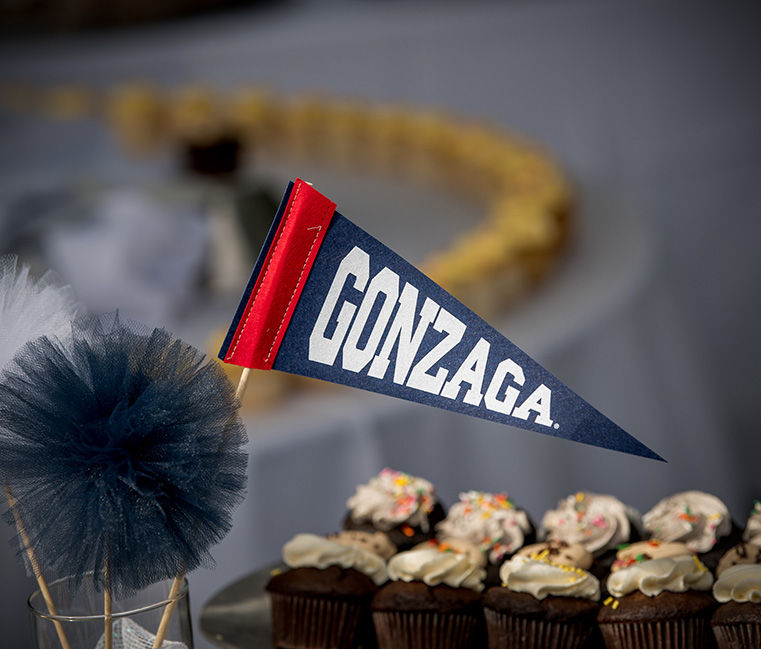 Decorative image includes a Gonzaga pennant flag and cupcakes in the background.