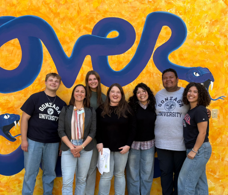 A group standing in front of a bright yellow wall.