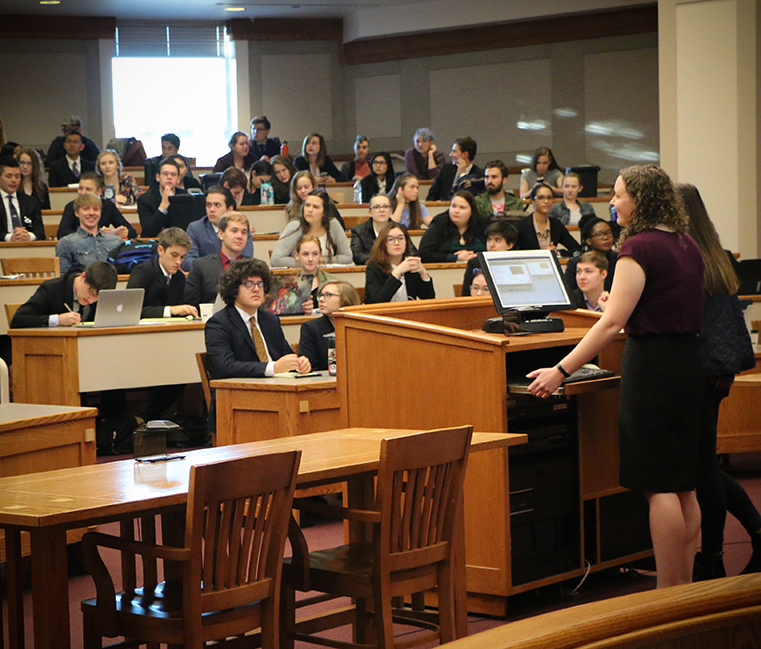 Mock Trial Student stands behind a lectern in front of a large audience.