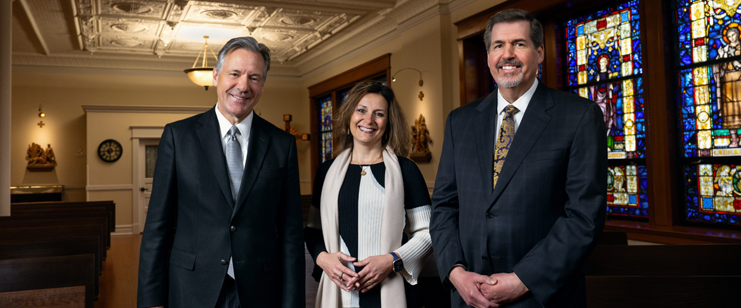 Board Chair Mike Reilly, President-elect Katia Passerini and Former President Thayne McCulloh smiling in the University Chapel.