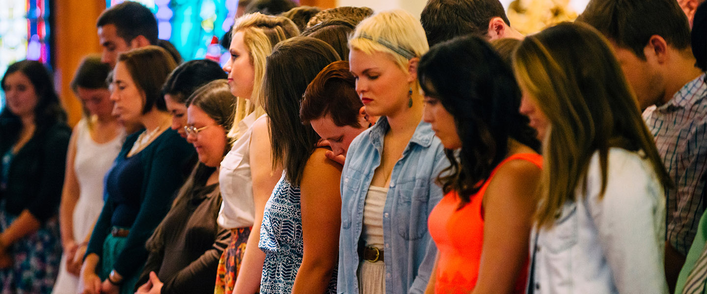 Students standing together in prayer.