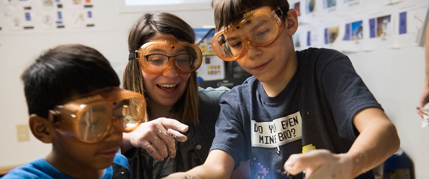 A teacher and two students work on an interactive experiment