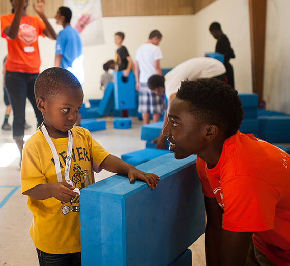 A student talks with a young child in a gymnasium