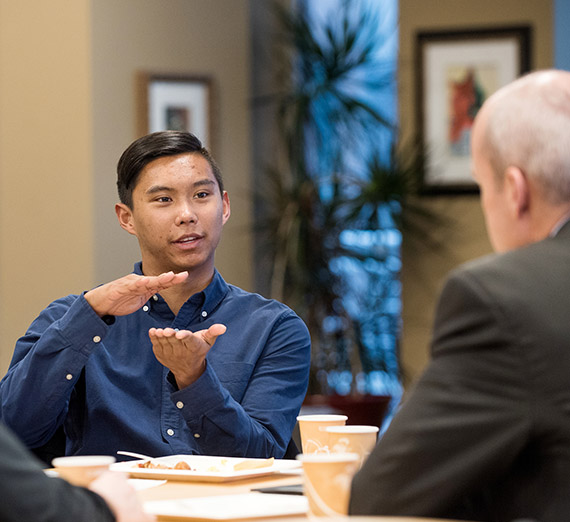 Student speaking with professionals at business breakfast.