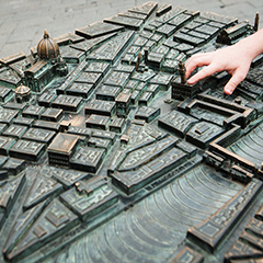 A student touches a building on a bronze 3D map of Florence
