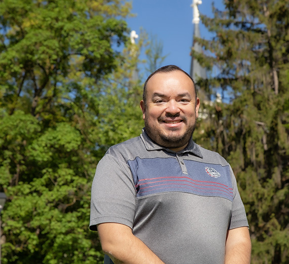 Master's in Theology and Leadership alumnus, Jose Francisco Gonzalez outside on campus with spires in background 