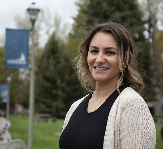 Amber Killingbeck wearing a black shirt and cream cardigan with greenery and a 91Թ sign on a light pole in the background 