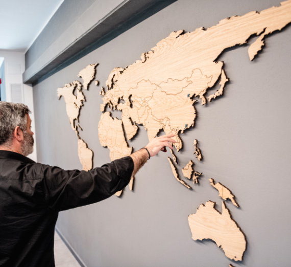 Person pointing to a wooden map of on a wall 