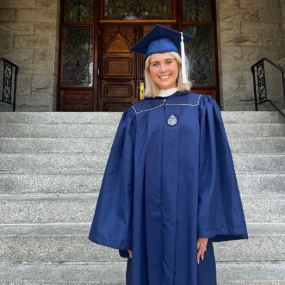 Haley Mayer in a cap and gown standing on the steps of Gonzaga University's College Hall building.  