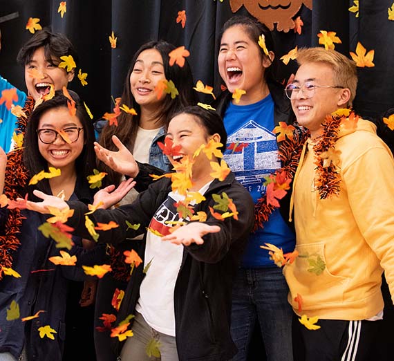 Student group shot with fall leaves surrounding them.