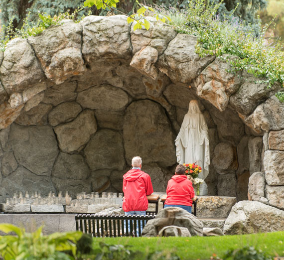 A couple prays at the grotto of Mary.