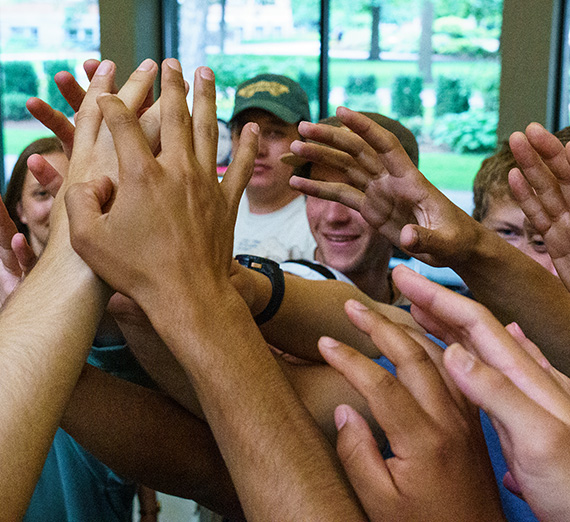 Hands raised in the air coming together.