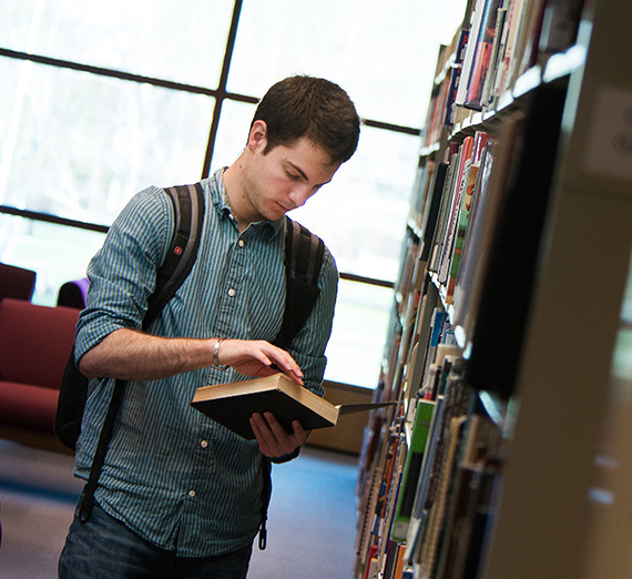 Student standing in the library reading