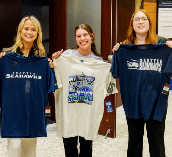Three students showcasing t-shirts