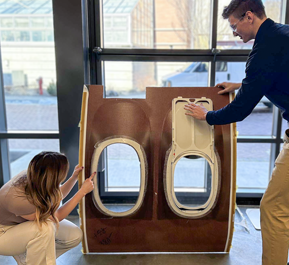 two students with an airplane side interior panel.