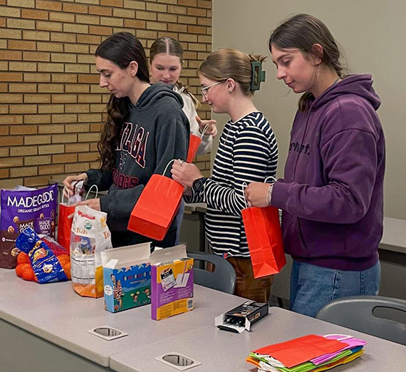 Four college women add snacks to party bags
