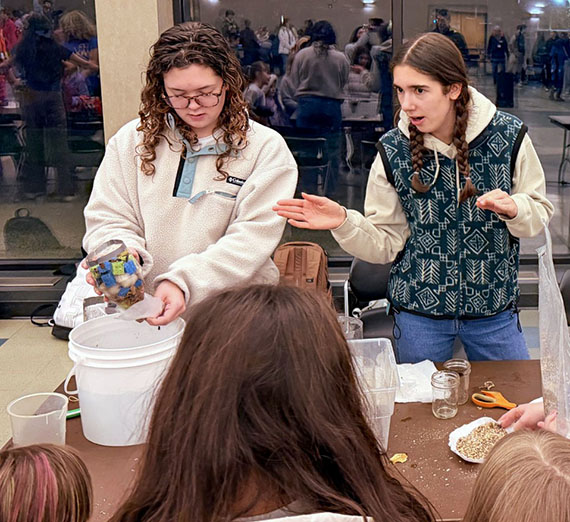 Students with a bucket prepare to show middle school students how to do a project