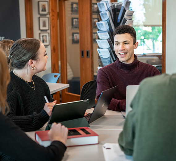 Two students in discussion at a table with laptops