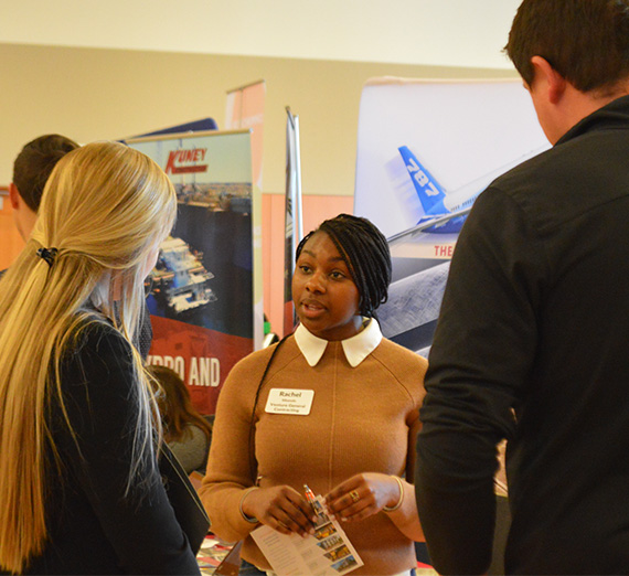 Student talks with business representatives at a career fair 