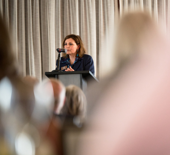 Photo of President Passerini speaking on stage from audience view