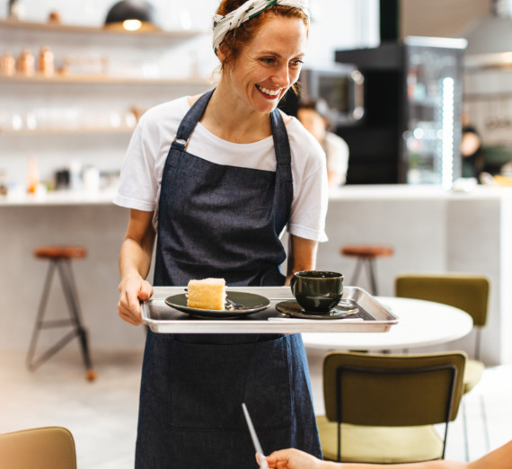 A waitress serving coffee and a pastry at a cafe