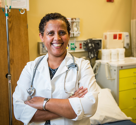 A nursing graduate poses in front of medical equipment.