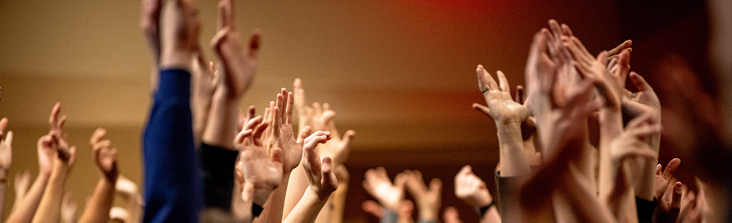Room full of people with their hands in the air.