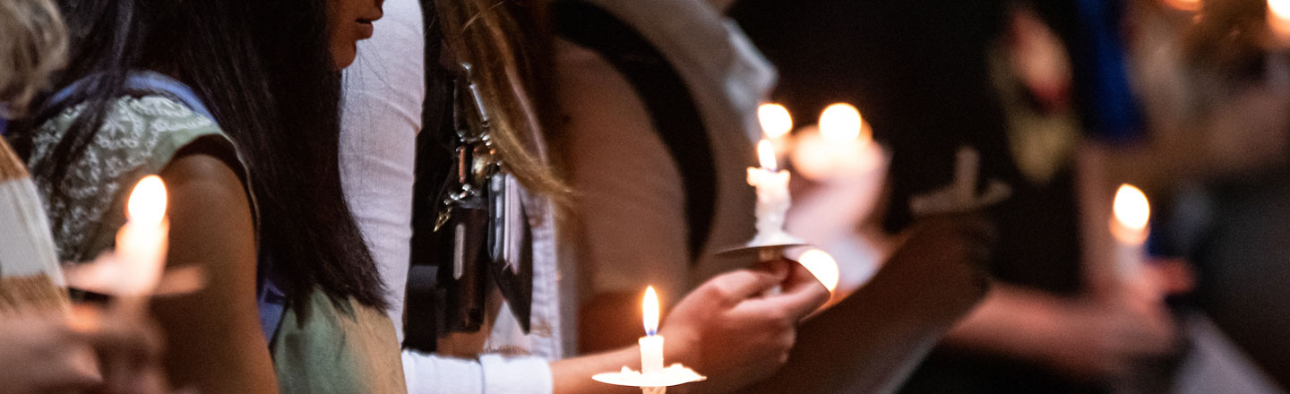Students praying and holding candles at a vigil.
