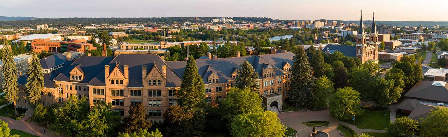 Aerial photo of Gonzaga University's campus on a sunny evening, featuring College Hall and St. Aloysius Church