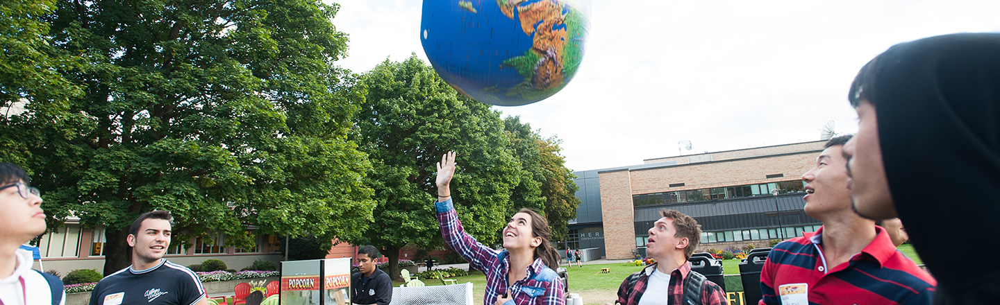 international students at the Welcome Back celebration tossing an inflateable globe into the air