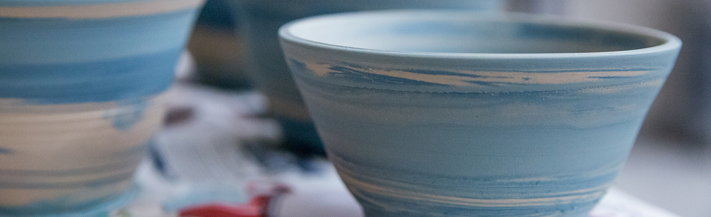 Ceramic bowls in various stages of being painted the color blue. Photo credit: Libby Kamrowski