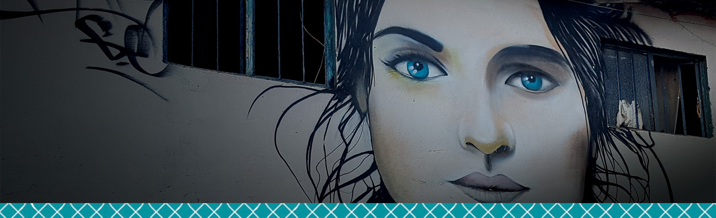 Painting of woman's face on a building wall.