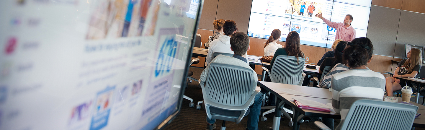 Students in a classroon with large computer monitors all around.