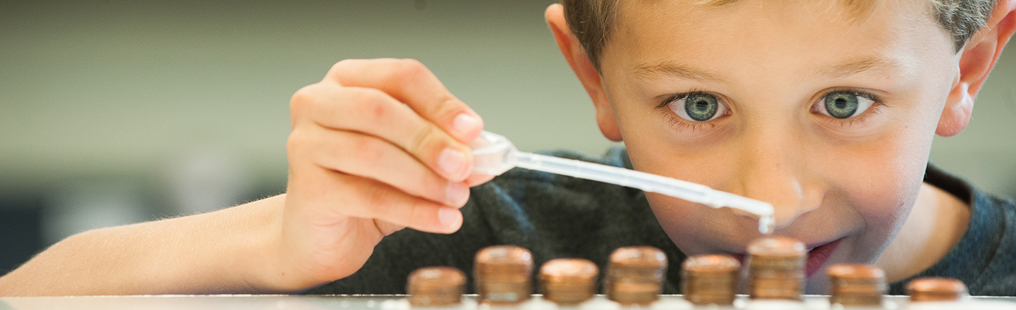 Young student conducts experiment using a dropper.