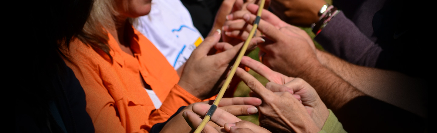 A group of people working together to hold a tent pole