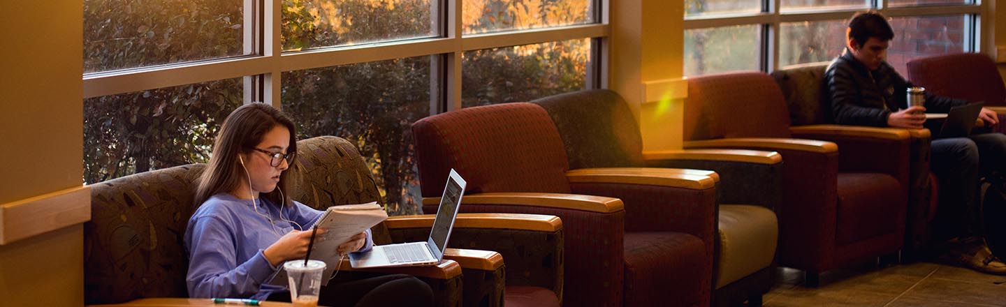 Women doing homework sitting in a chair in Jepson lounge
