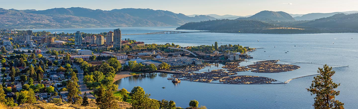 A high resolution panorama of the Kelowna British Columbia skyline and Okanagan Lake with the R W Bennett Bridge in the background, from Knox Mountain at sunset